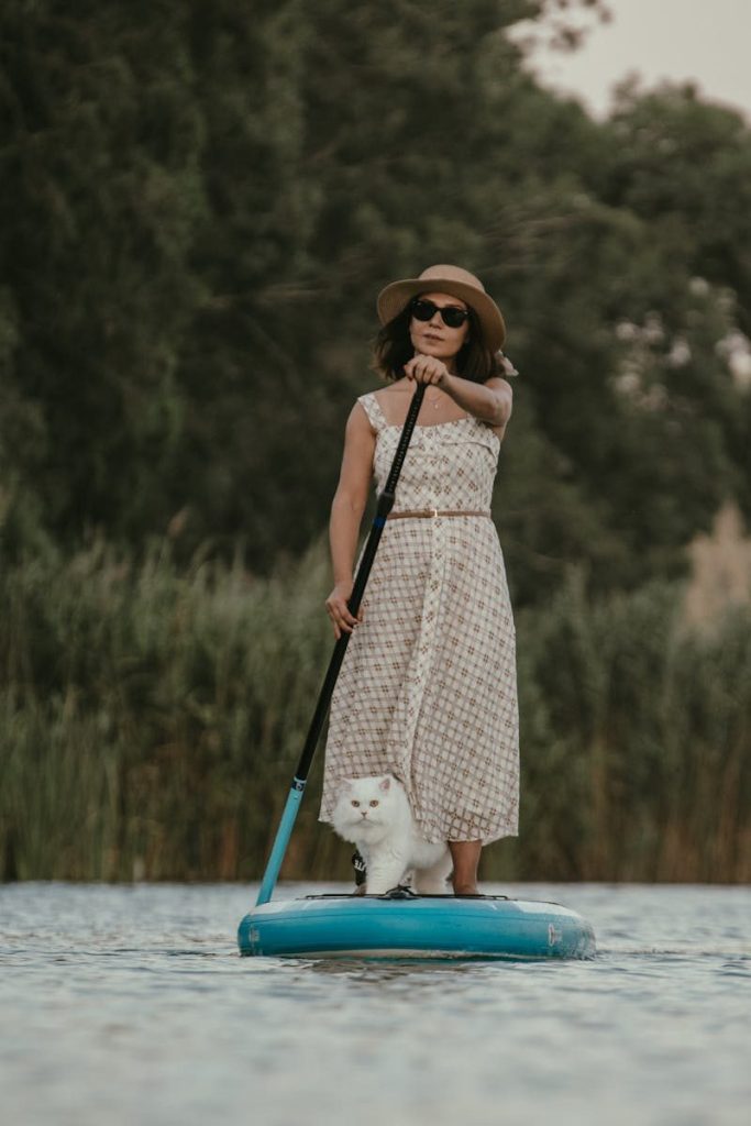 A woman paddleboards with her cat on a serene summer lake in Adana, Türkiye.