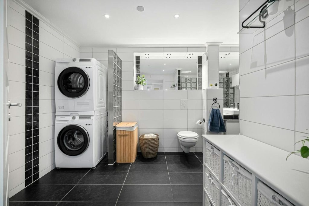 Sleek and modern bathroom with integrated laundry, tiled walls and floor, and stylish decor.