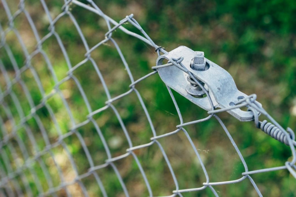Detailed view of metal wire mesh fence with bolts for security and protection outdoors.