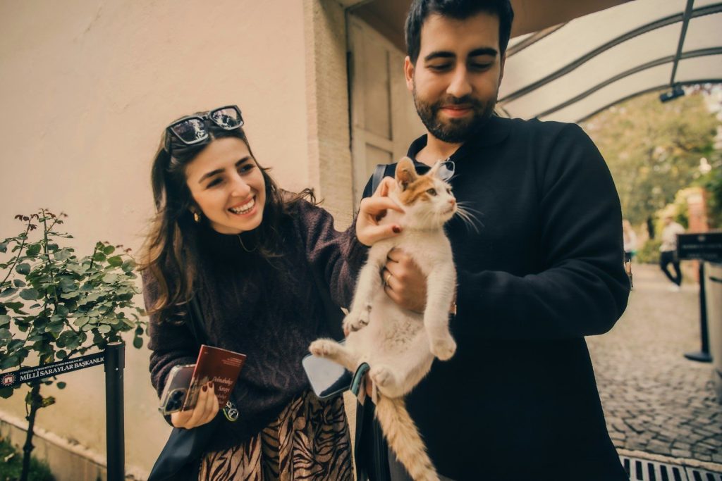 A smiling woman and man holding a cat