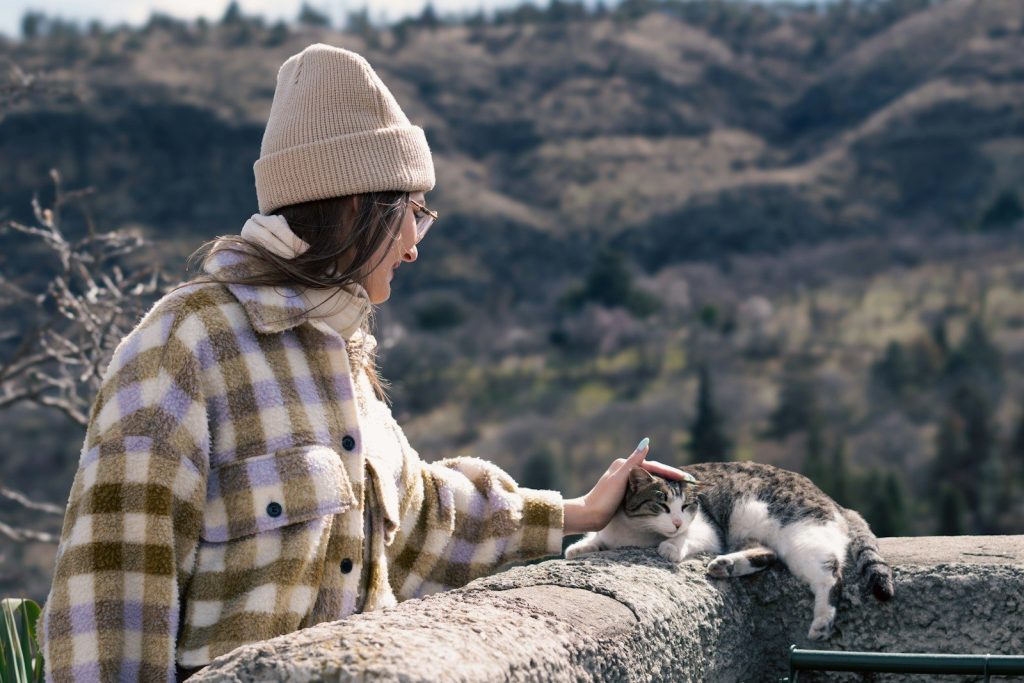 a woman petting a cat on top of a stone wall