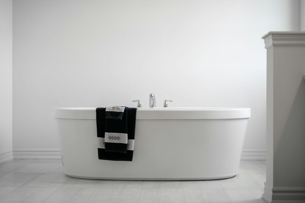 A modern bathtub with towels draped over the side.