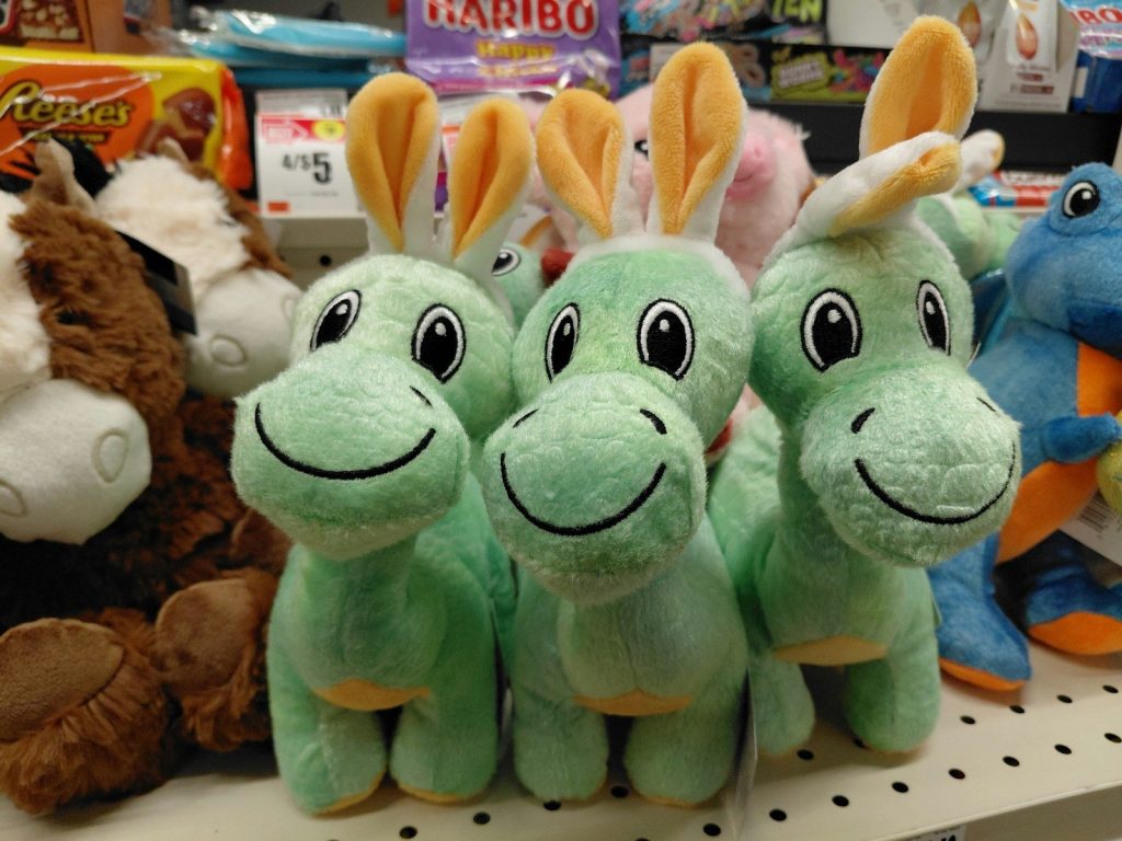 Three green dinosaur plush toys with bunny ears.