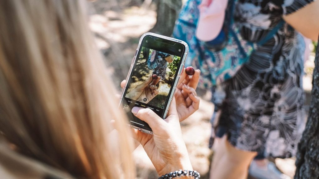 woman in black and white shirt holding black smartphone