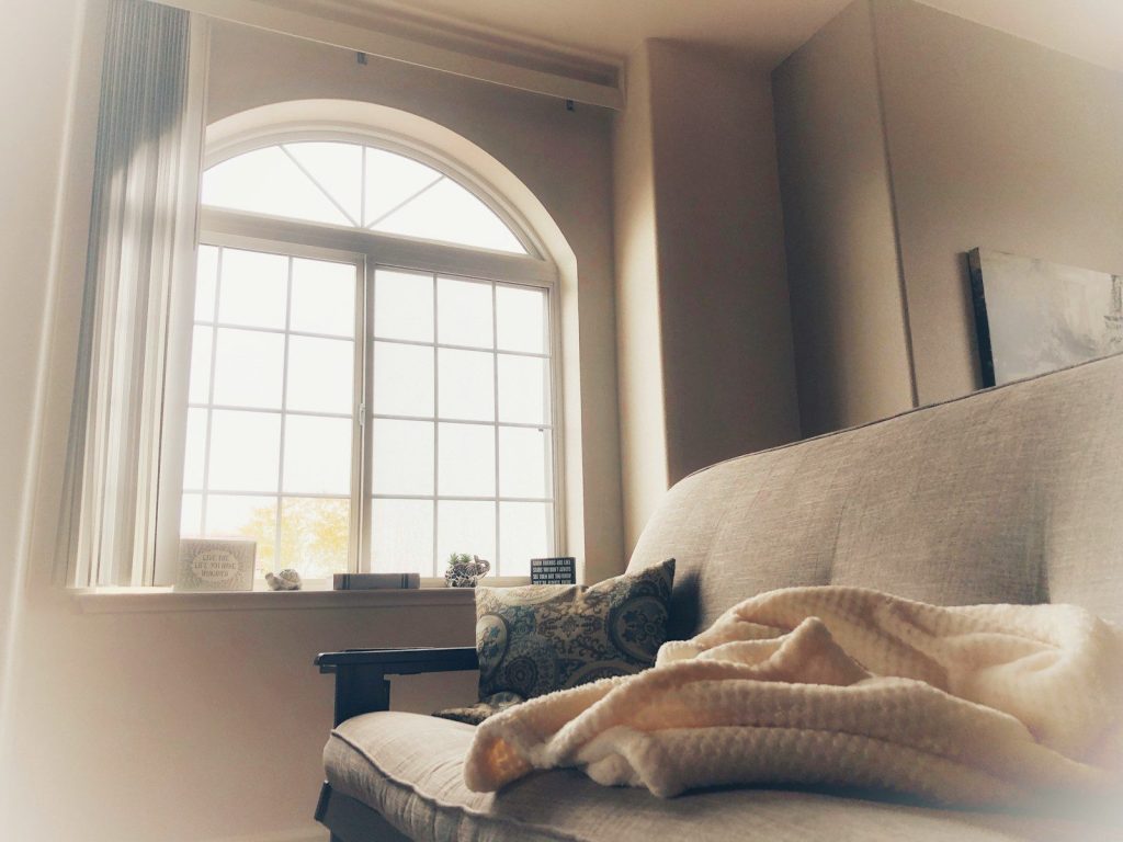 a couch with a blanket on it in front of a window