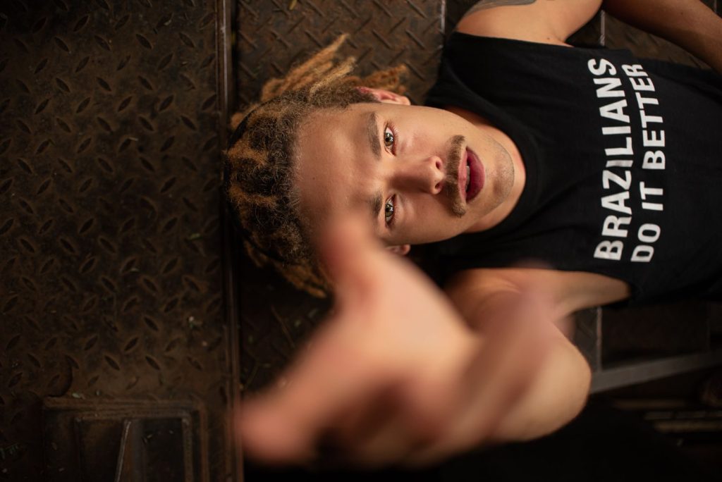 Man with stylish dreadlocks posing on metal stairs in São Paulo.