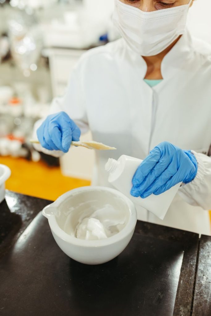 A scientist in a lab coat and mask blends chemical compounds for a research project.