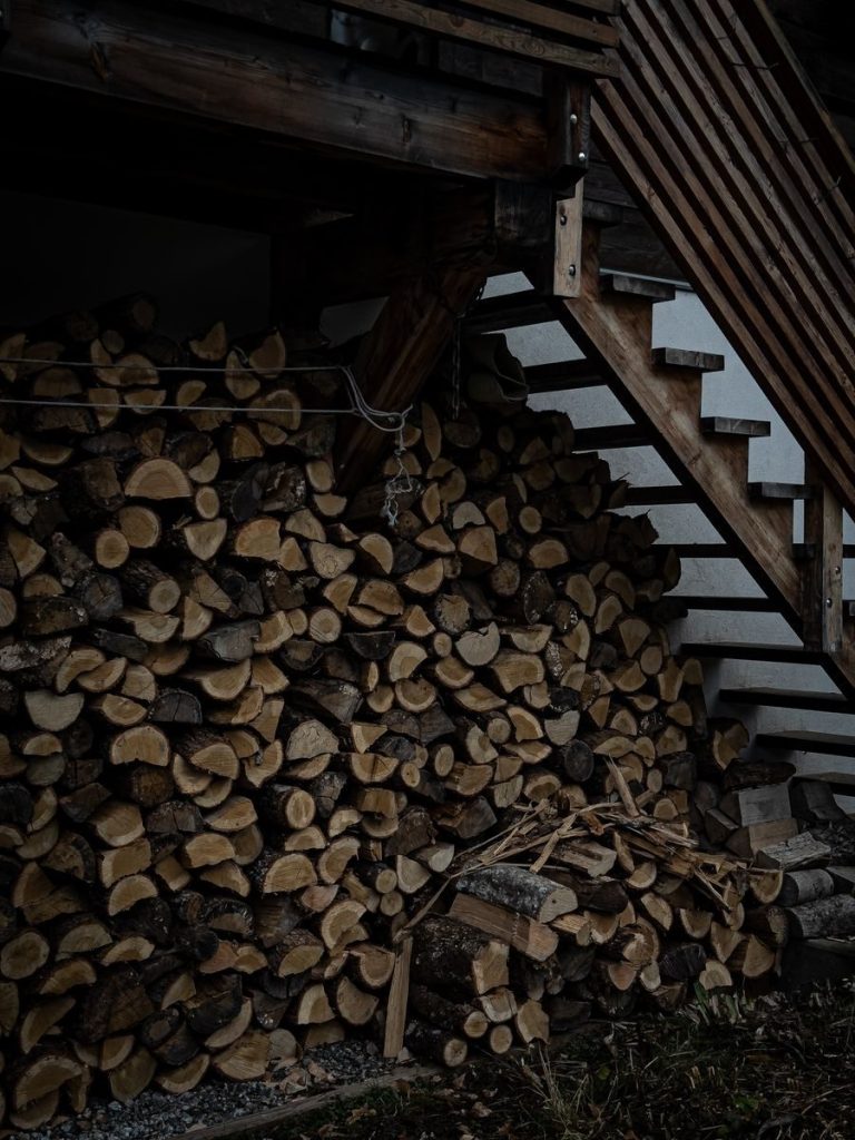 Stacked firewood under stairs, perfect for rustic and outdoor themes.