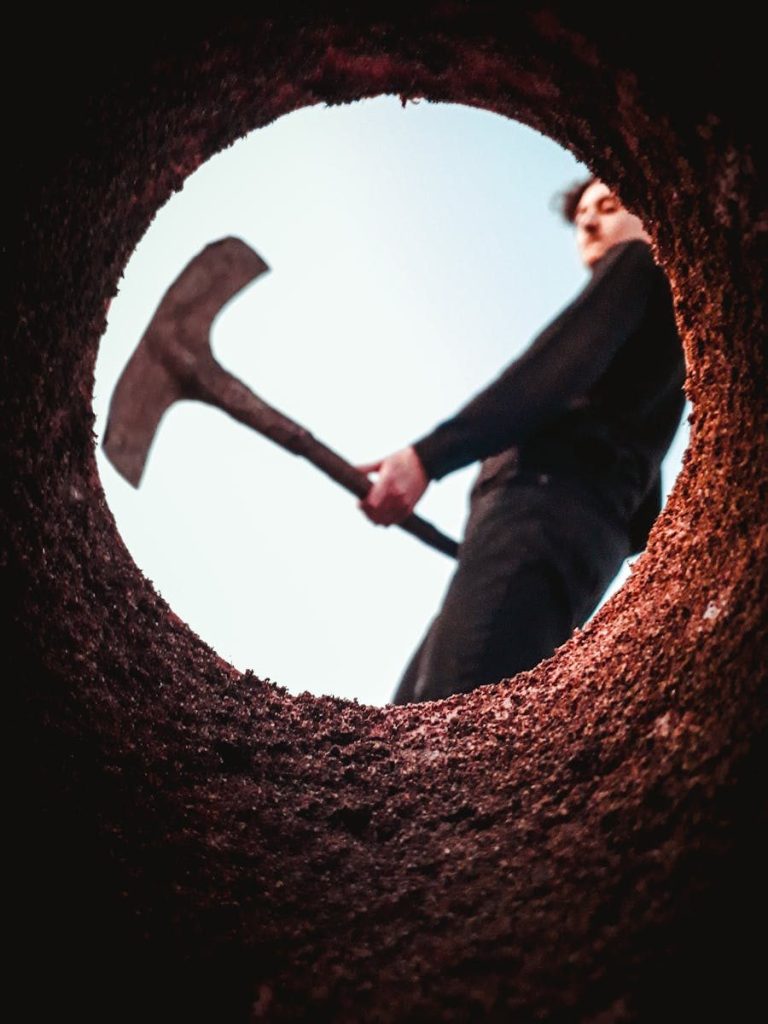 From below of crop male farmer with gardening tool in hand working with soil in farm