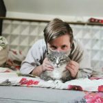 Man chilling with his grey tabby cat on a colorful bed. Cozy and peaceful moment.
