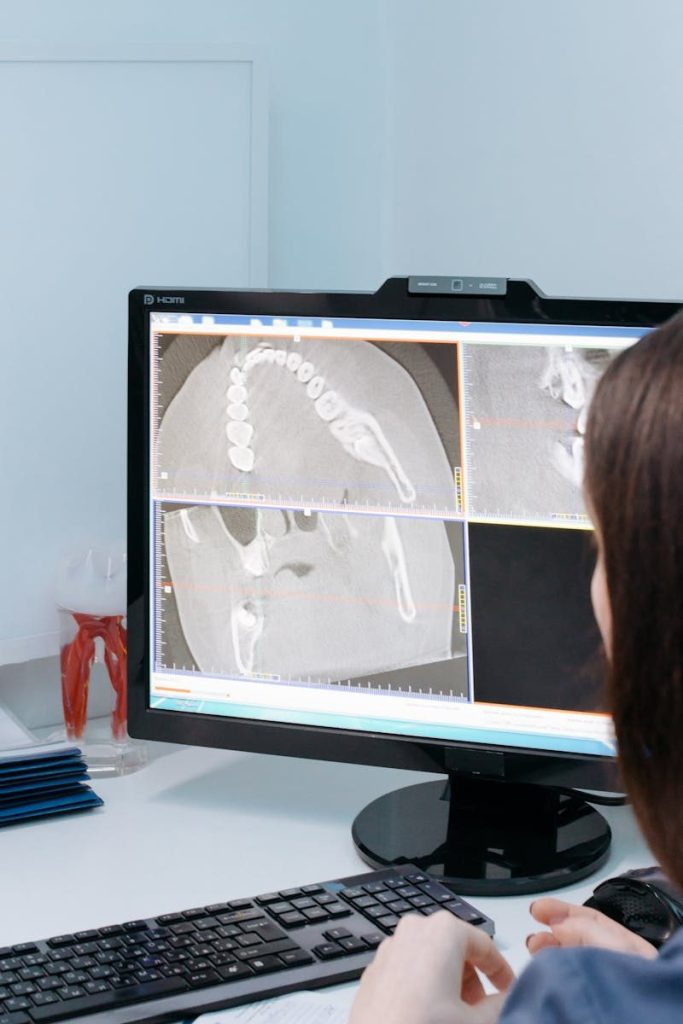 Dental professional analyzing digital jawbone X-rays on a computer screen for diagnostic purposes.