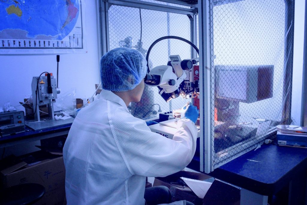 person in front of white microscope