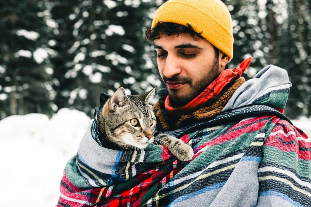a man holding a cat wrapped in a blanket