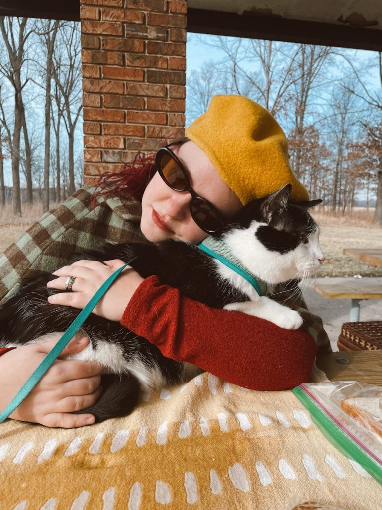 Woman hugging a black and white cat outdoors