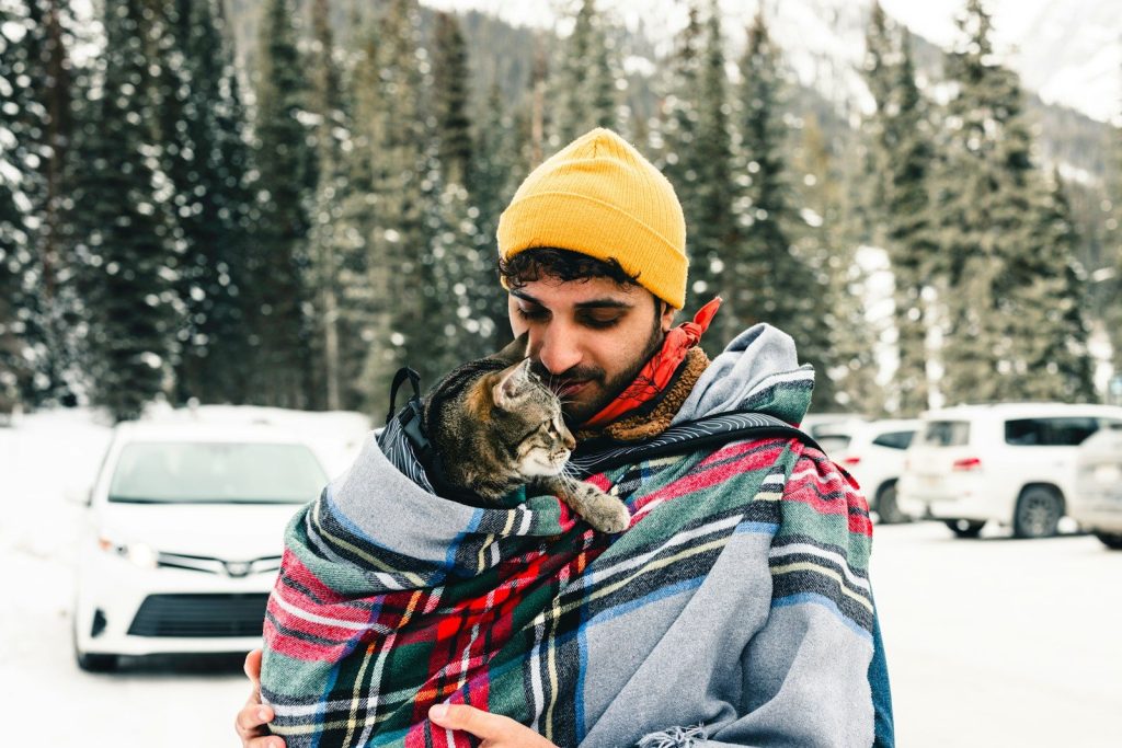 a man holding a cat wrapped in a blanket
