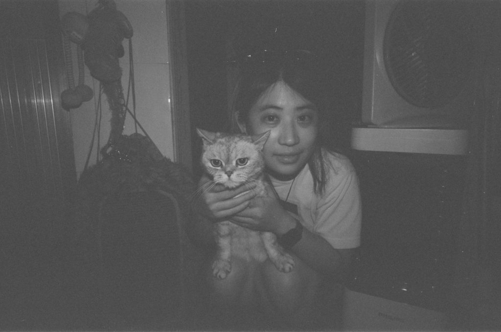 A person holds a cat in a dimly lit room.
