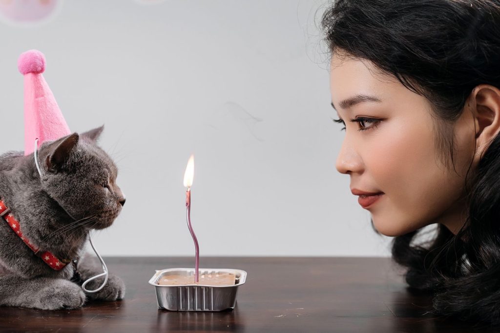 A woman and her cat share a special birthday moment with a candlelight.