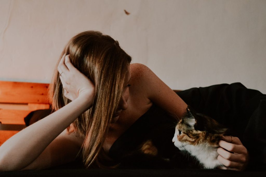 A serene moment of a woman and her cat lying on the bed, captured indoors.
