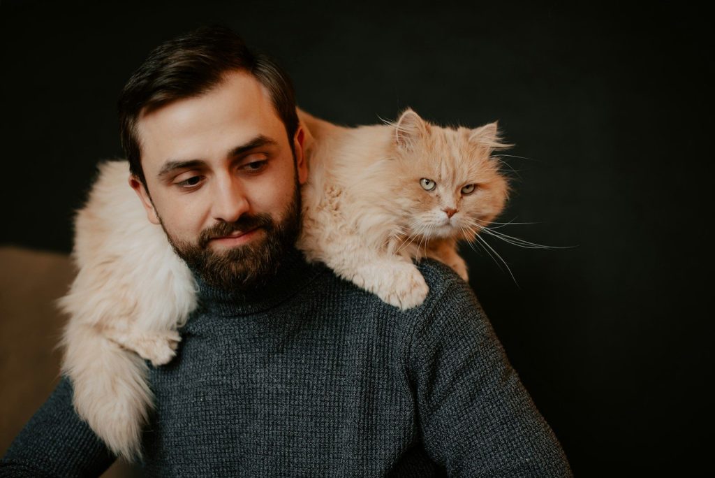 a man holding a cat on his shoulders