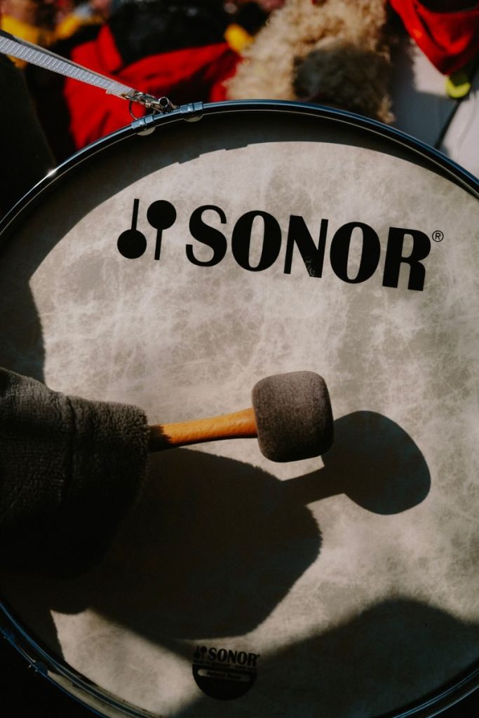 Close-up of a hand playing a Sonor bass drum at an outdoor festival.