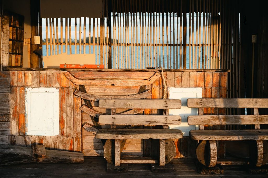 Sunlit rustic fishing hut with wooden benches and bamboo fencing, capturing coastal charm at sunset.