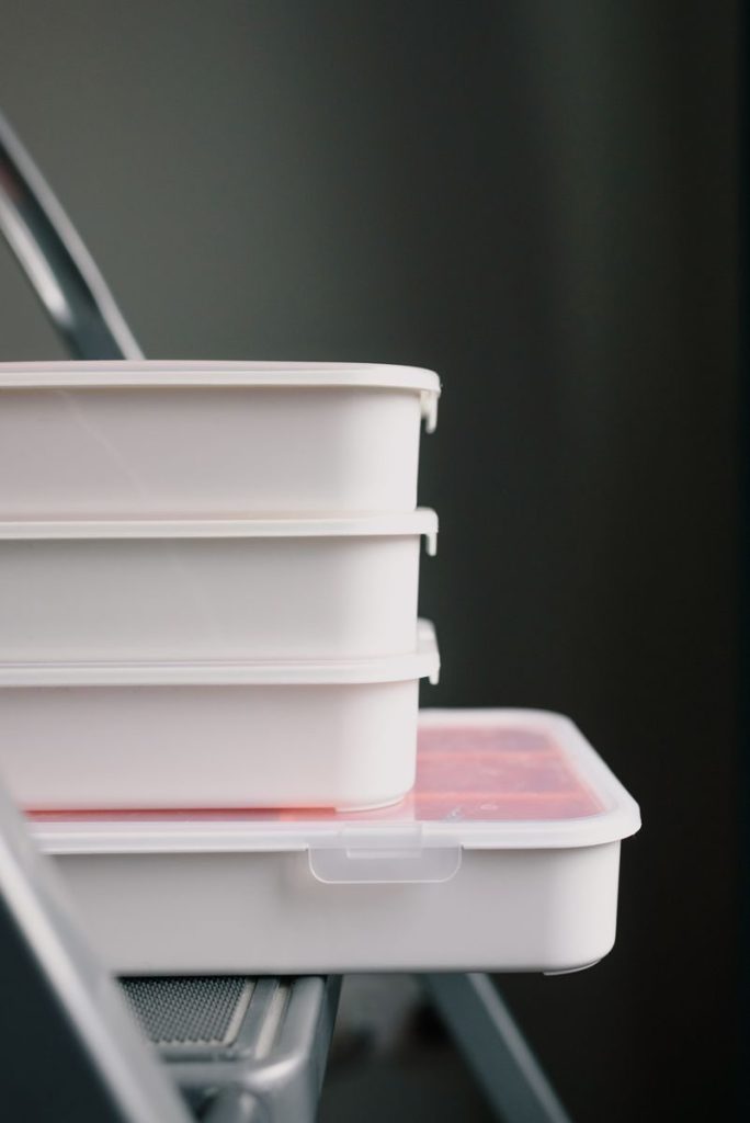 Plastic containers with tools on metal ladder in room during renovation in workshop